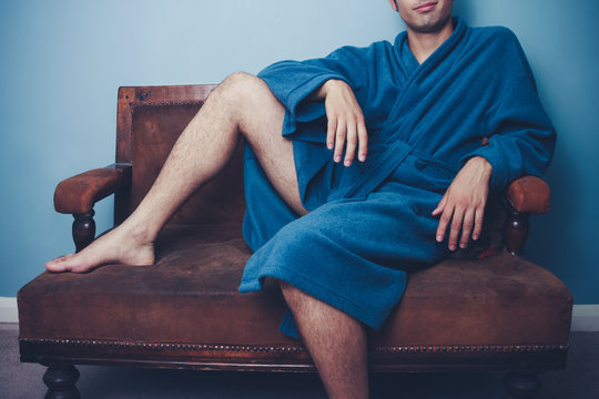 Young man in robe posing on vintage sofa