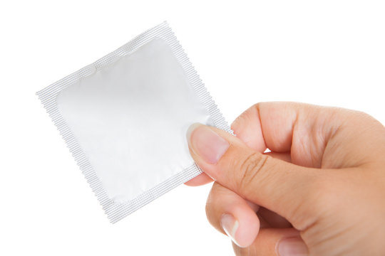 Close-up of hand holding condom packet