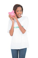 Smiling woman shaking piggy bank by her ear