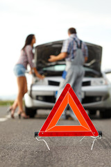 Woman driver and repairman talking in front of broken car