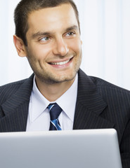 Smiling businessman working with laptop at office