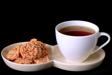 Afternoon tea and crispy rice snack on black background.
