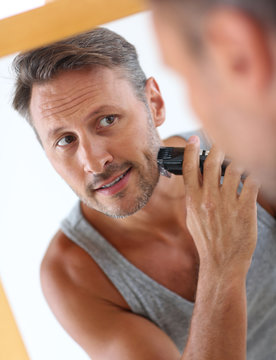 Handsome guy shaving in front of mirror