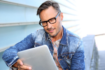 Man with blue jeans jacket using digital tablet