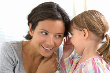 A little girl telling her mother a secret