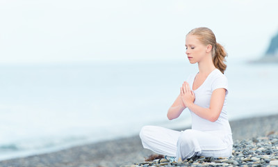 woman meditating in  lotus yoga on beach