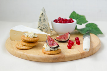 Cheese plate with berries , crackers and figs.