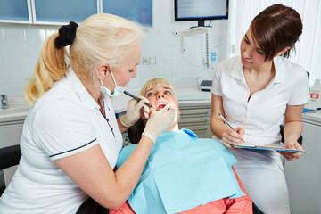 Zahnarzthelferin in Ausbildung schaut Zahnarzt zu