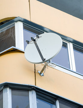 White sat TV dish on a balcony