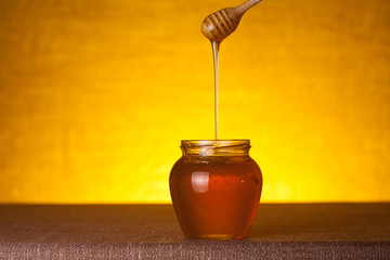 Honey jar with dipper and flowing honey