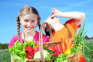 Two little girls with basket of vegetables