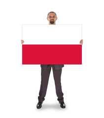 Fototapeta premium Smiling businessman holding a big card, flag of Poland