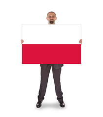 Obraz premium Smiling businessman holding a big card, flag of Poland