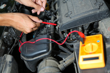 Auto mechanic uses multimeter voltmeter to check voltage level