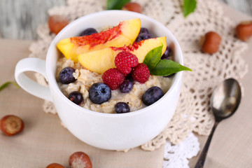 Oatmeal in cup with berries on napkins on wooden table