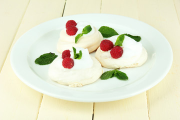 Tasty meringue cakes with berries on wooden table