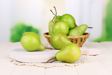 Pears on wooden cutting board, on light background
