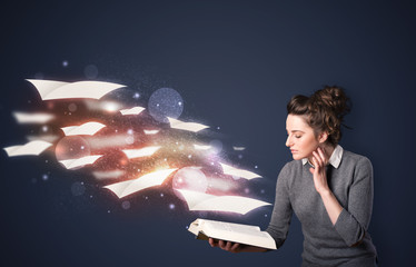 Young lady reading a book with flying sheets coming out of the b