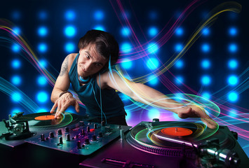 Young Dj mixing records with colorful lights