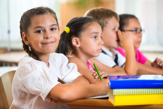 Four Diligent Pupils Studying At Classroom