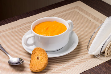 Pumpkin soup in white bowl with crouton