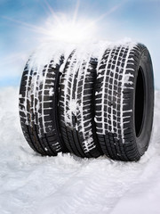 Snowy winter tyres in front of blue sky with sunlights