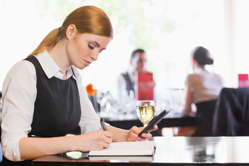 Concentrated businesswoman holding phone while writing