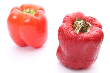 Fresh and wrinkled peppers on white background