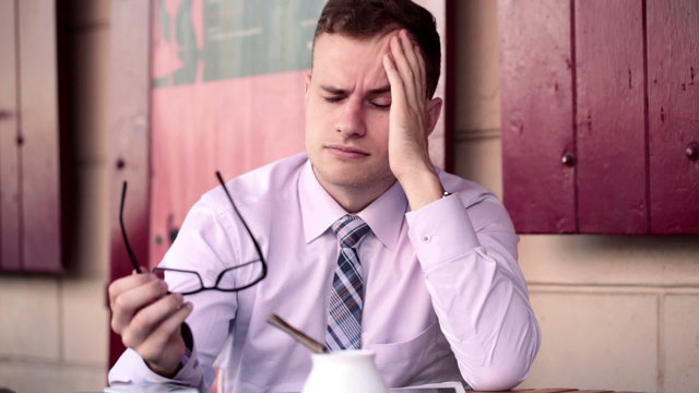 Young tired businessman having headache in cafe