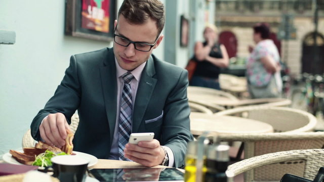 Businessman with smartphone during lunch in cafe
