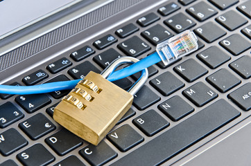 Internetkabel und Zahlenschloss auf Computertastatur als Symbol für die Verschlüsselung des Datentransfers