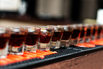 Red, strong alcoholic drink in small glasses on bar