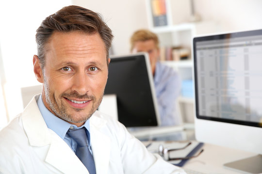Portrait of smiling doctor sitting in front of computer