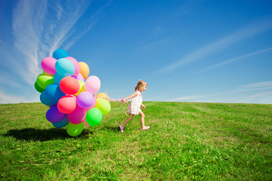 Little Girl Holding Colorful Balloons. Child Playing On A Green