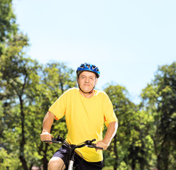 Mature man in sportswear posing on a mountain bike in a park