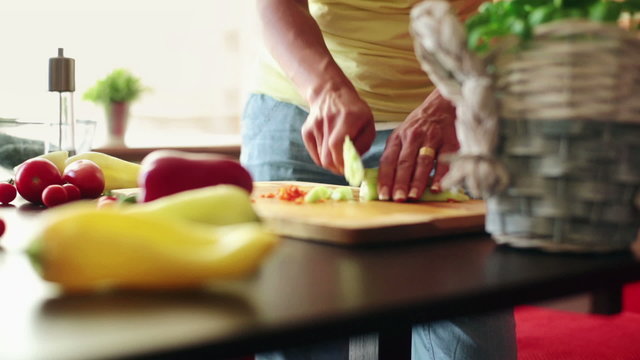Woman hands slicing cucumber in kitchen