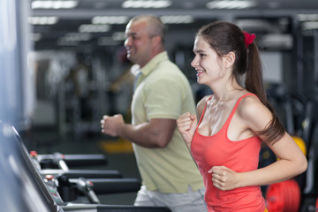 Fototapeta na wymiar Sportive woman and man are jogging treadmill