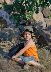 Young boy waiting alongside his rucksack