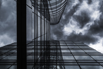 high rise glass building under rain cloud sky