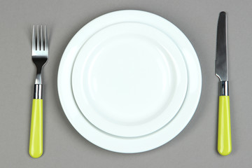 Knife, color plate and fork, on color background