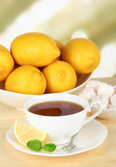 Cup of tea with lemon on table on light background