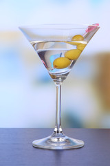 Martini with green olives on table in bar