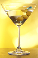 Martini with green olives on table in bar
