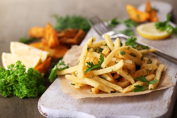 French fries on tracing paper on board on wooden table