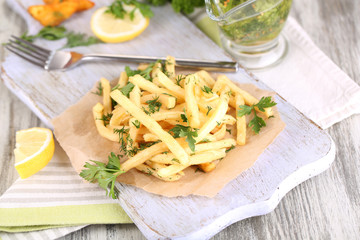 French fries on tracing paper on board on napkin wooden table
