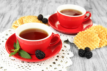 Cups of tea with cookies and blackberry on table close-up