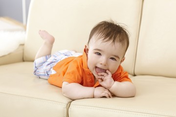 Fototapeta premium Beautiful baby boy lying on sofa