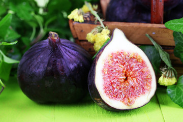 Ripe figs in leaves on wooden table close-up