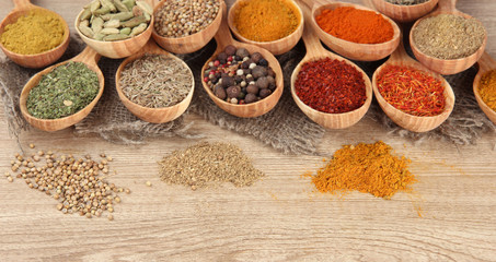 Assortment of spices in wooden spoons on wooden background