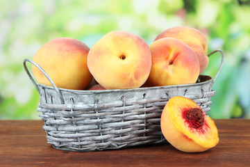 Ripe sweet peaches in wicker basket, on bright background